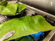 Running the banana leaf over the flame to soften it Running the banana leaf over the flame to soften it