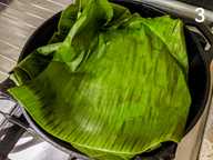 Banana leaves covering the fish and spice mixture in a cast iron skillet Banana leaves covering the fish and spice mixture in a cast iron skillet