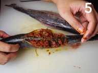 Dua tangan menunjukkan ikan yang telah diisi penuh sambal di atas papan pencincang plastik. Dua tangan menunjukkan ikan yang telah diisi penuh sambal di atas papan pencincang plastik.